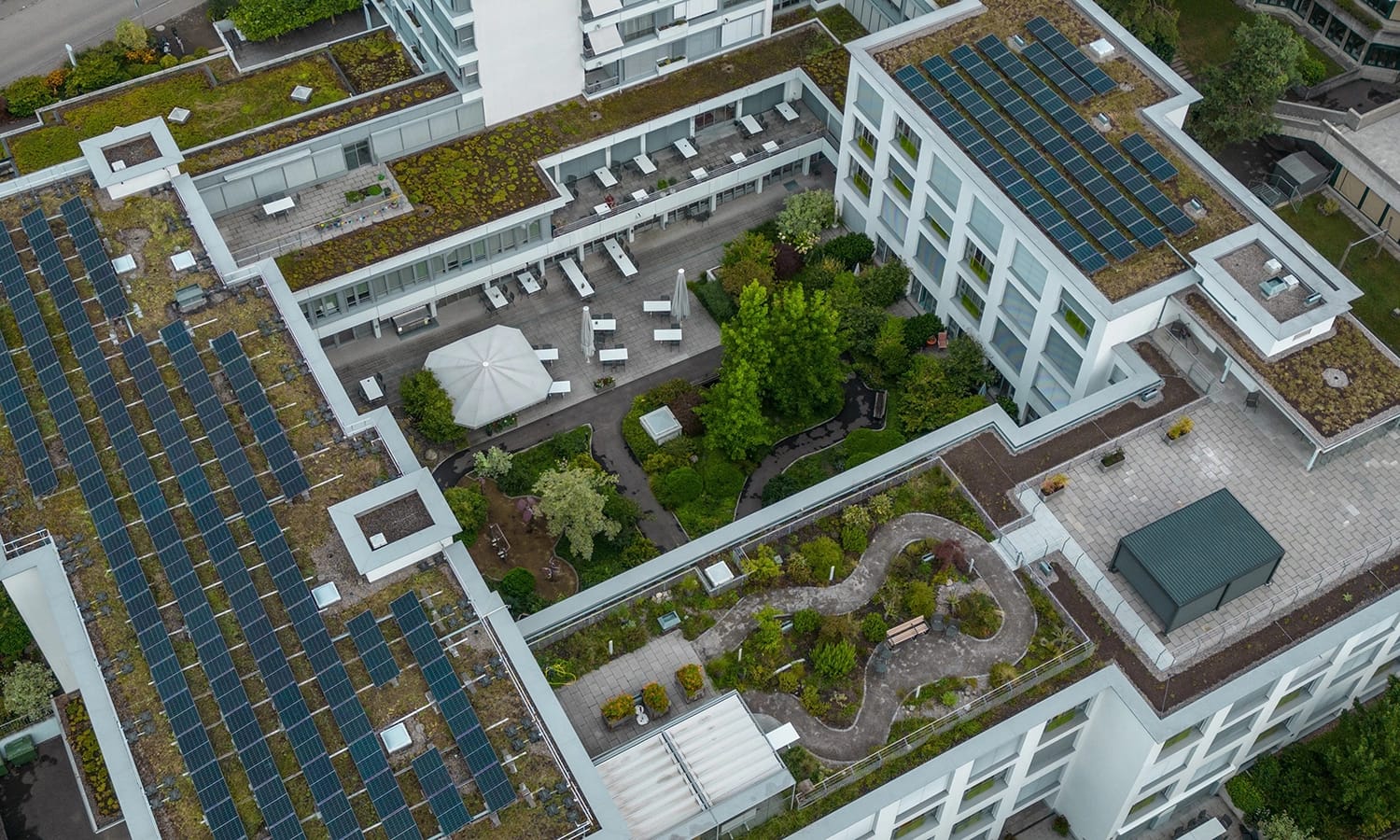 Luftaufnahme eines modernen Büro‑ und Wohnkomplexes mit begrüntem Dach, Solarzellen und Dachgarten – nachhaltige Architektur und Energieeffizienz bei Lobos.
